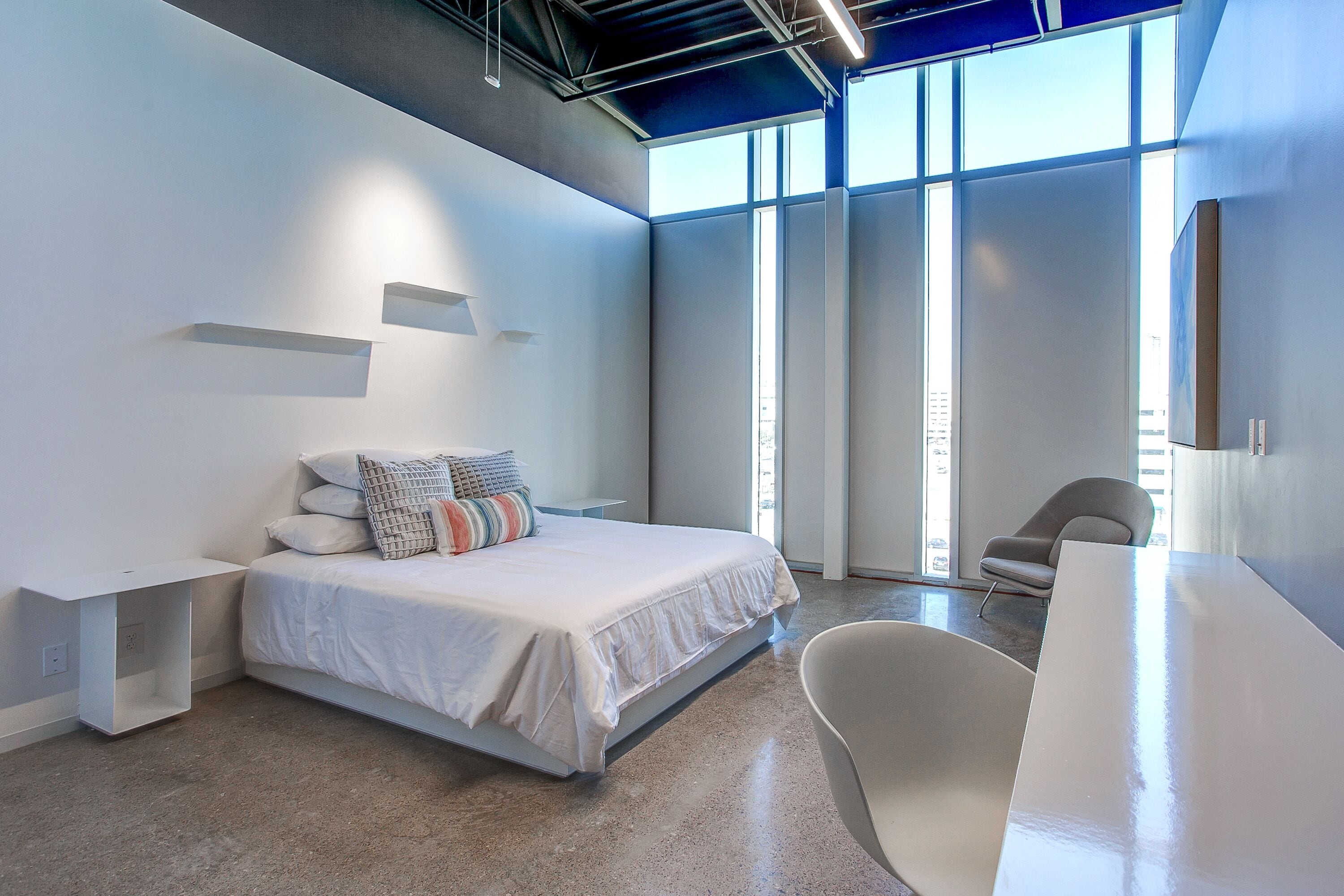 A modern bedroom with a large bed, a desk, and a chair.