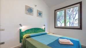 A bedroom with a bed, a window with a view of trees, and wall decorations. - Cosy Holiday Apartment "Villetta Vista Mare" with Wi-Fi, Balcony and Terrace (Santa Margherita di Pula)