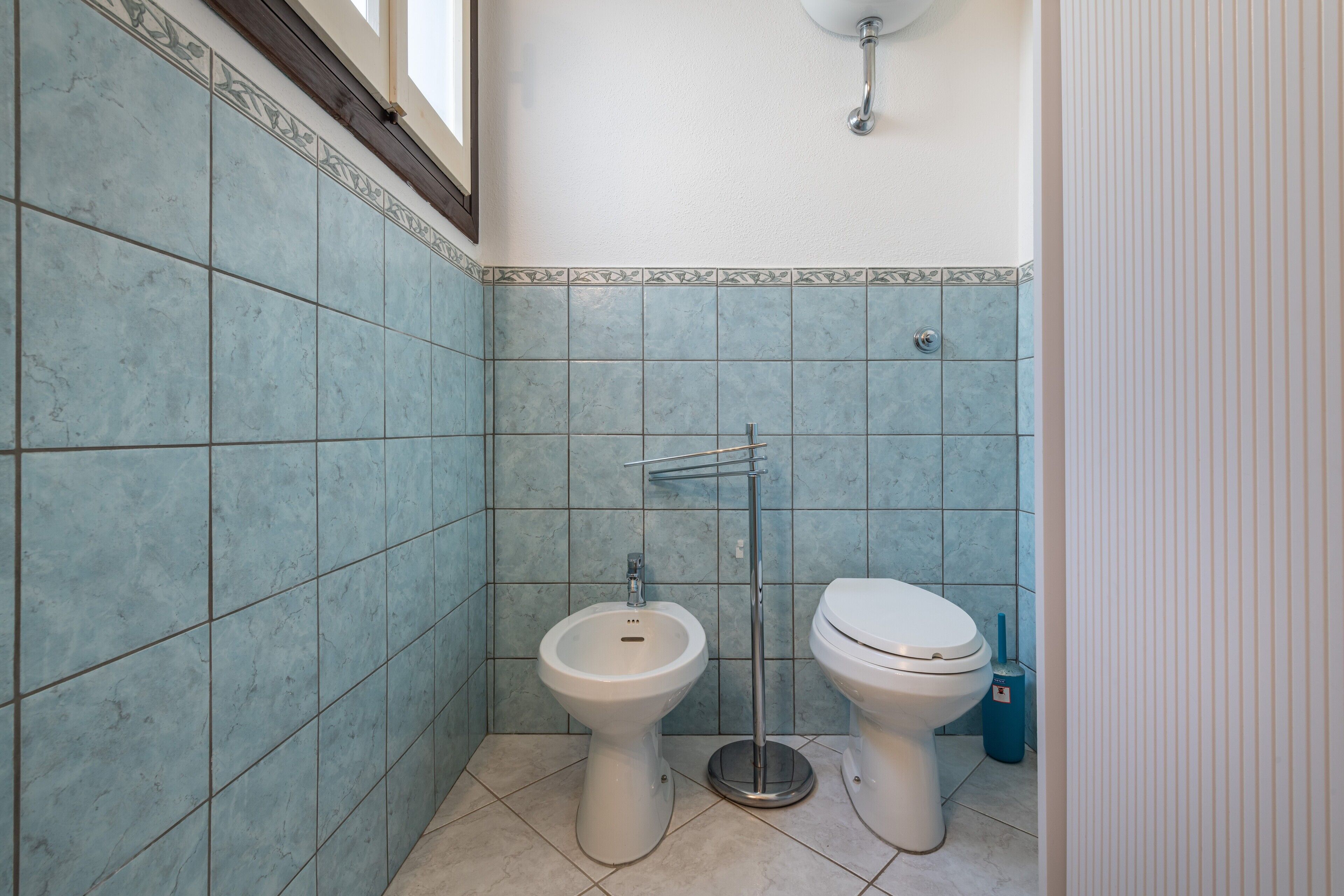 Ein Badezimmer mit WC, Bidet und Fliesenwänden.
