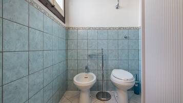 Ein Badezimmer mit WC, Bidet und Fliesenwänden.