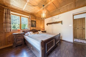 A wooden-paneled bedroom with a bed, nightstand, and a wall-mounted lamp. - Beautiful Holiday Home “Ferienhaus in der Blaiche”  with Mountain View, Wi-Fi, Balcony, Garden. (St.Leonhard Passeier)