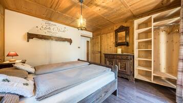 A wooden-paneled bedroom with a bed, a nightstand, a dresser, a mirror, and a wardrobe.