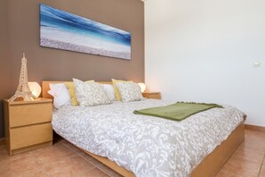 Ein Schlafzimmer mit einem Bett, Nachttischen, einem an der Wand hängenden Gemälde und einem dekorativen Eiffelturm-Modell.