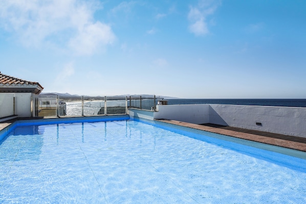 Une piscine sur le toit offrant une vue dégagée sur l’océan et les montagnes lointaines.