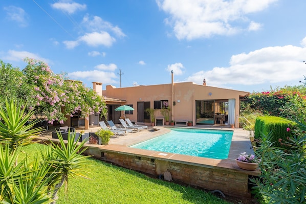 A modern house with a swimming pool, a patio with lounge chairs, and a well-maintained garden. - Beautiful Villa with Pool, Wi-Fi, Terraces, Garden and Gorgeous View; Parking Available (santanyi)