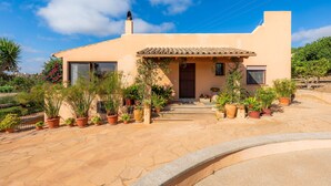 A modern house with a tiled roof, a front porch with potted plants, and a clear blue sky. - Beautiful Villa with Pool, Wi-Fi, Terraces, Garden and Gorgeous View; Parking Available (santanyi)