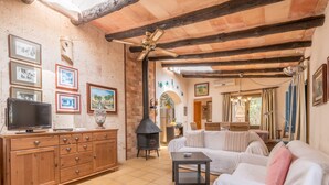 A living room with a fireplace, wooden furniture, and a television. - Natural stone villa with pool & garden - Villa Sa Barraca (Santanyi)
