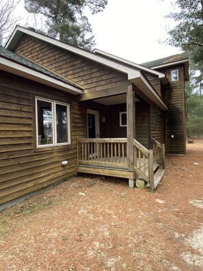 A wooden cabin with a porch and a small deck.