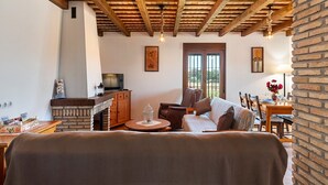 A cozy living room with a wooden ceiling, a fireplace, a television, and a dining area with a table and chairs. - In a quiet location with sea view - El Mirador de Castilnovo (El Palmar (Cádiz))