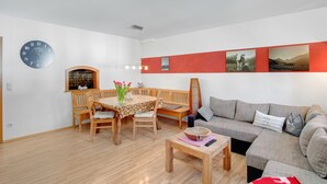 Ein Wohnzimmer mit einem Holzesstisch, einer Couch und einer Wanduhr.
