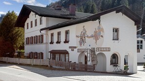 Ein weißes Gebäude mit geneigtem Dach und zahlreichen Fenstern, mit einem Wandgemälde an der Seite.