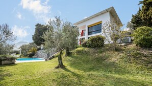 Une maison moderne avec une piscine, entourée de verdure et d’arbres.