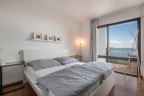 Ein Schlafzimmer mit Bett, Nachttischen, einer Lampe, einem Fenster mit Aussicht und einem Bild an der Wand.