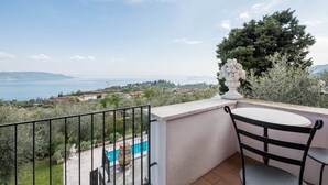 Un balcon avec vue sur la mer, une piscine et une statue.