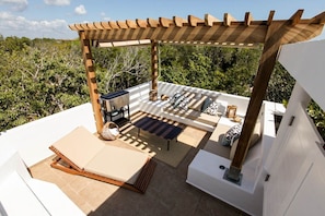 Une terrasse extérieure dotée d’une pergola, d’un espace salon et d’un barbecue encastré.