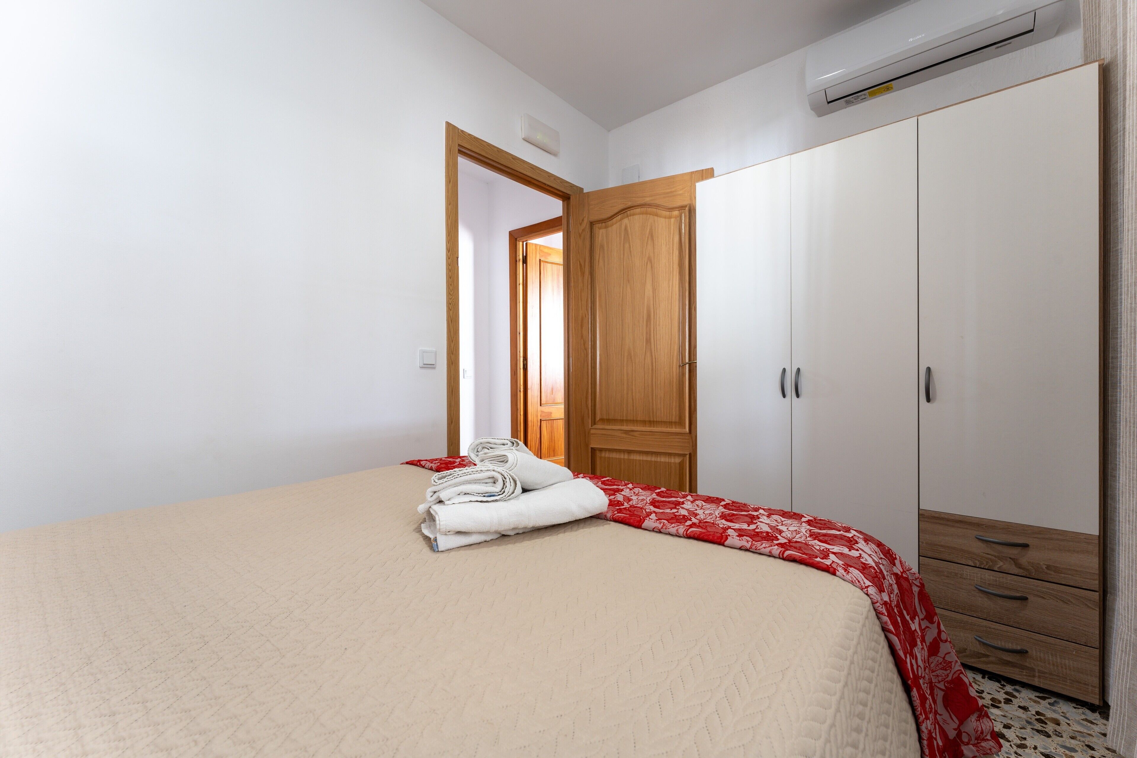 Un dormitorio con cama, armario, puerta y aire acondicionado.