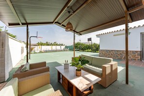 An outdoor patio with wicker furniture, a marble table, and a hanging light fixture.