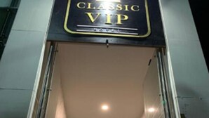 Een hotelentree met een 'Classic VIP' bord, een kroonluchter en een trap naar binnen.