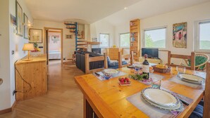 A spacious dining area with a wooden table set for a meal, a cozy seating area with a sofa and chairs, and a bookshelf filled with books. - Beautiful private villa for 6 people with WIFI, TV and terrace (Lerici)