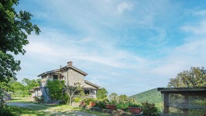 A stone house with a gravel driveway, surrounded by greenery and a hilly landscape. - Beautiful private villa for 6 people with WIFI, TV and terrace (Lerici)