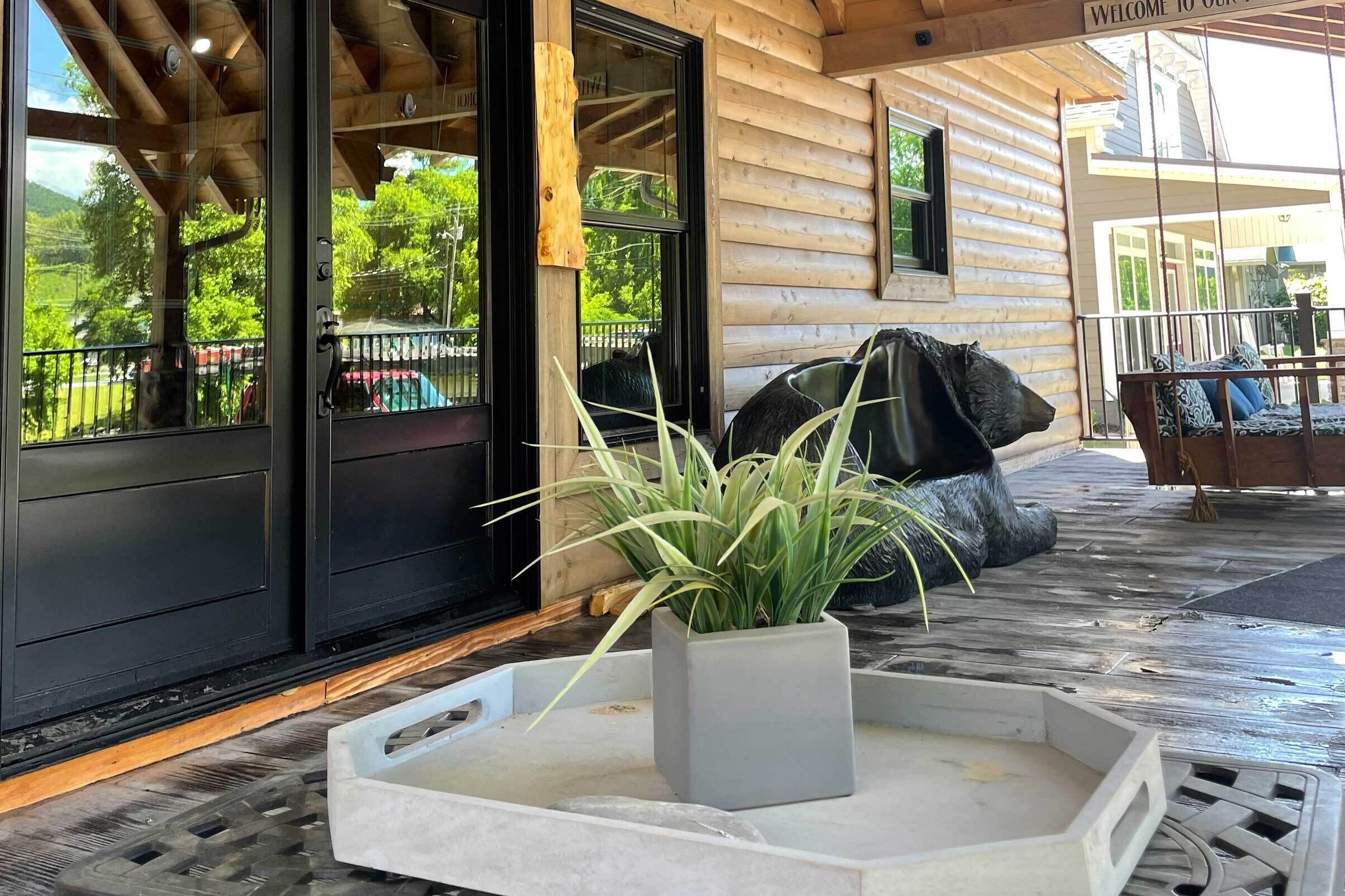 A wooden cabin with a porch, a black door, and a welcome sign.