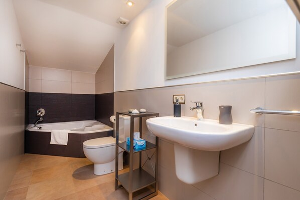 A modern bathroom with a bathtub, toilet, sink, and a mirror.