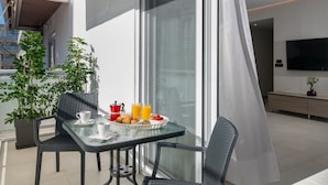 Un balcon avec une table préparée pour le petit-déjeuner, comprenant une tasse de café, des croissants et un panier de fruits.