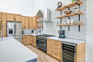 A modern kitchen with wooden cabinets, a stainless steel refrigerator, a built-in oven, and a wine cooler. - Gorgeous Newly Renovated Carlsbad Beach Home (Carlsbad)