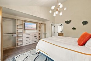 Een slaapkamer met een bed, een kledingkast, een televisie en een badkamer.