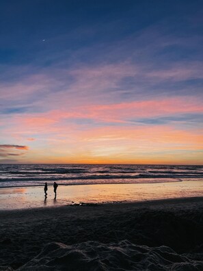 A beach scene with two people walking along the shore during sunset. - Gorgeous Newly Renovated Carlsbad Beach Home (Carlsbad)