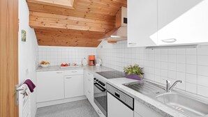 A modern kitchen with white cabinets, a wooden ceiling, a built-in oven, a dishwasher, and a sink.
