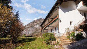 A two-story building with a balcony, a staircase, and a mountain in the background.