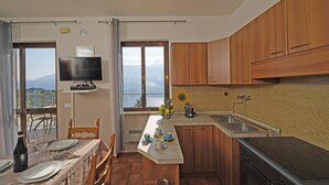 Eine Küche mit Holzausstattung, einem eingebauten Backofen, einer Spüle und einem Essbereich mit Tisch für zwei Personen.