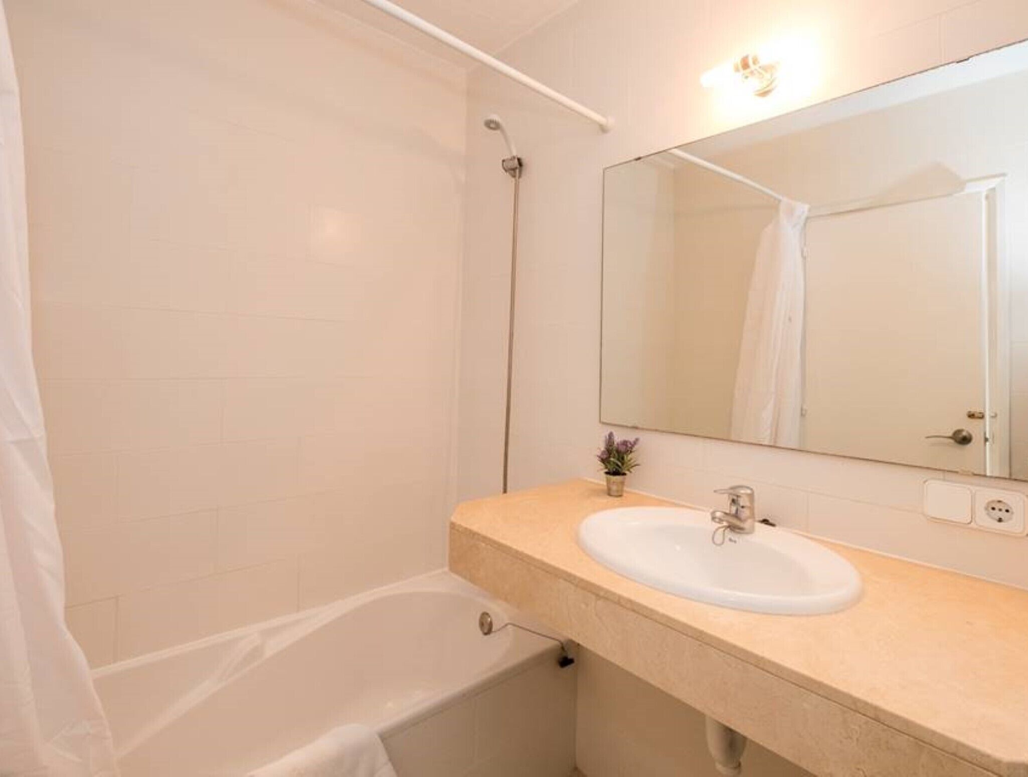 A bathroom with a bathtub, a sink, a mirror, and a shower.