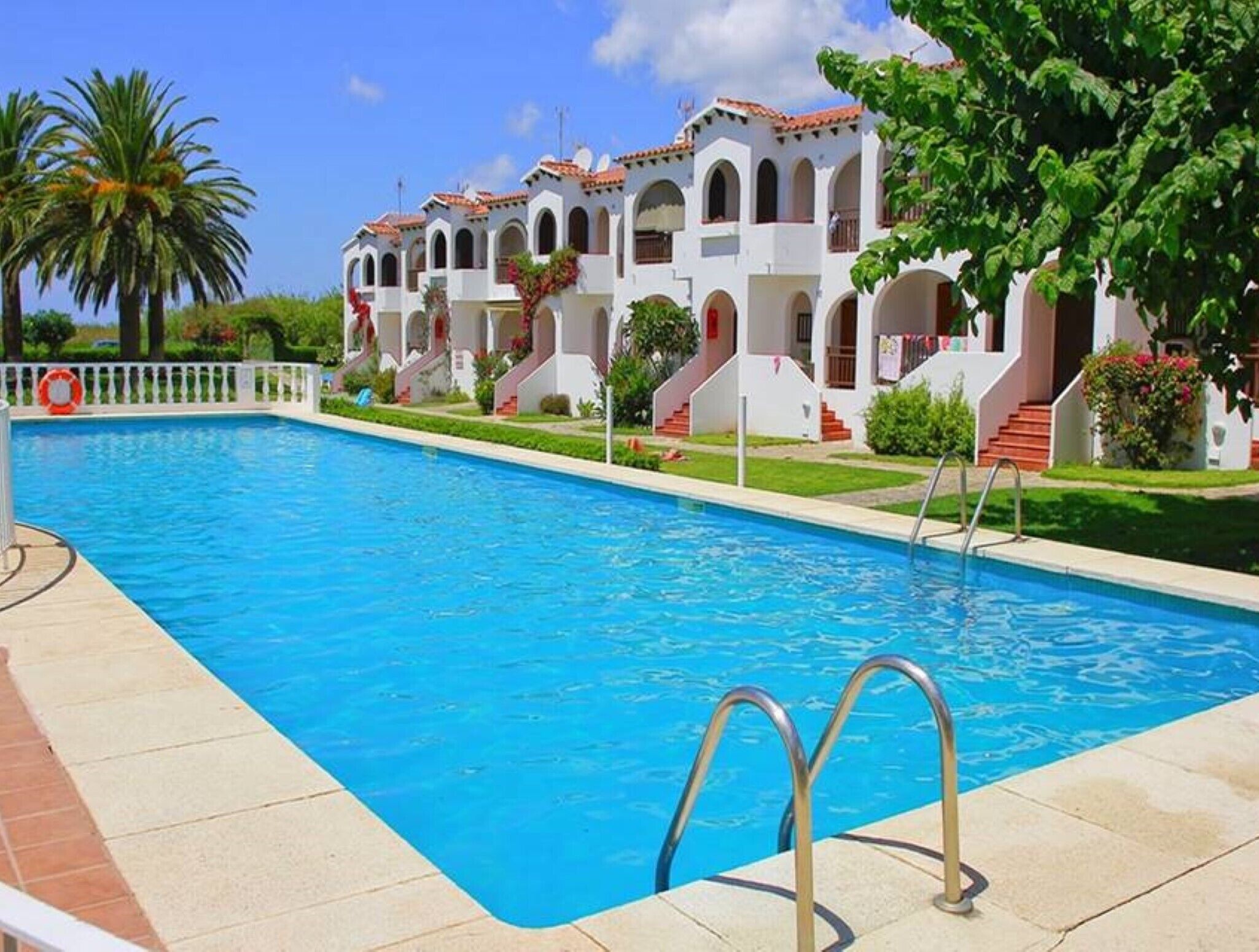 Una piscina con un edificio blanco al fondo.