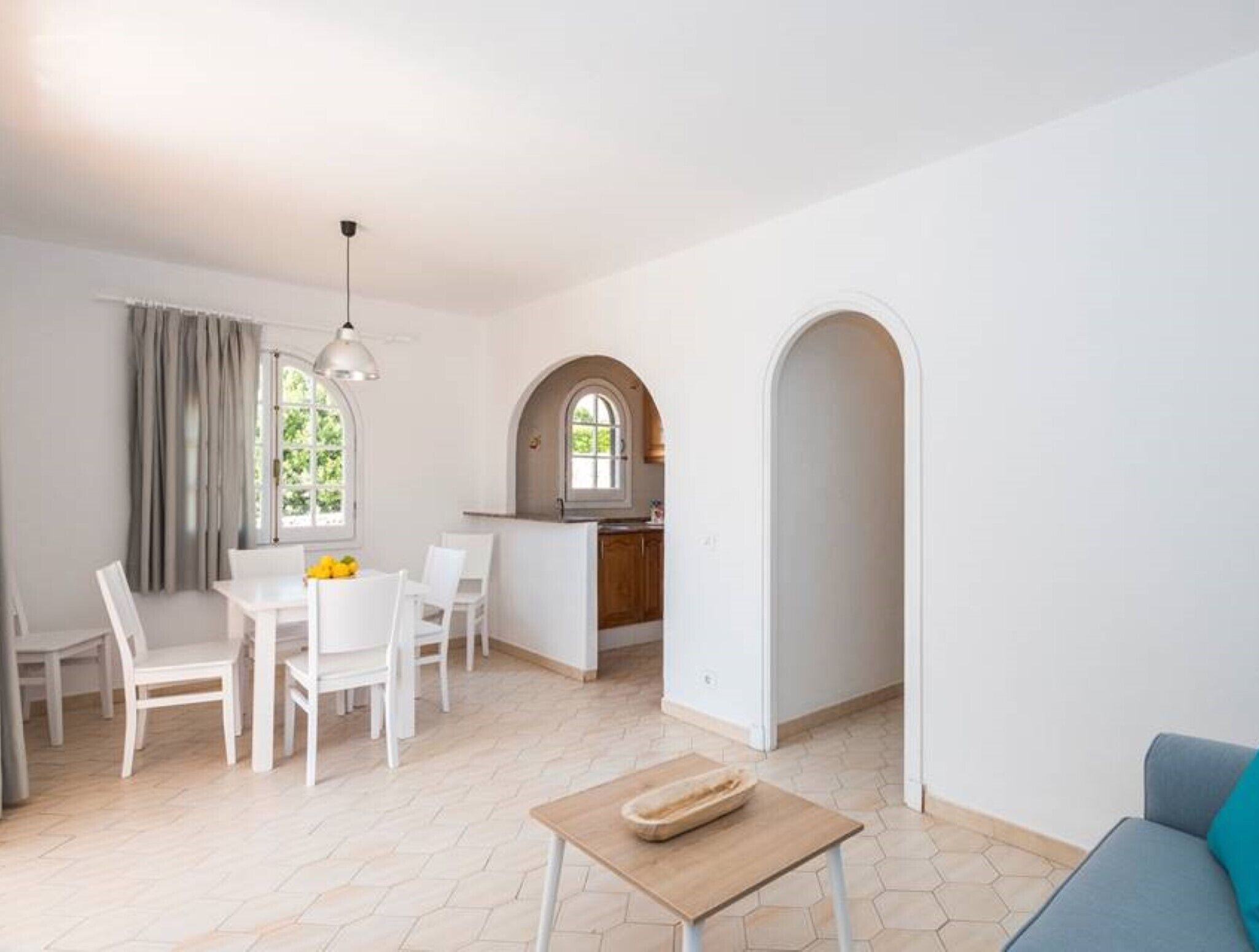 Un grand espace de vie comprenant une table à manger, des chaises, un canapé et une cuisine en arrière-plan.