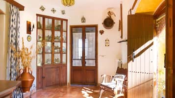 Un intérieur traditionnel avec une porte en bois, un banc et un vase contenant des plantes séchées.
