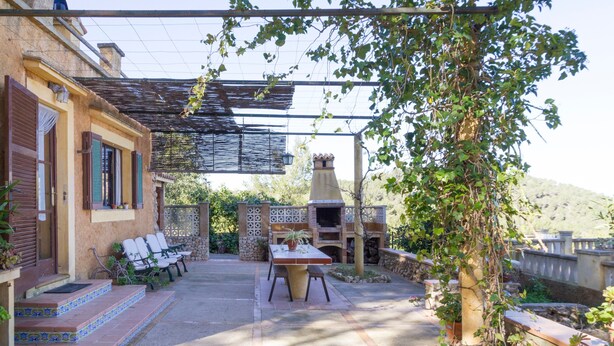 A patio with a table and chairs, a brick oven, and a pergola. - Idyllic location with pool - Villa Bonavista (Felanitx)