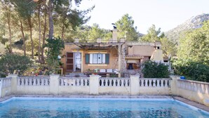 A house with a swimming pool, a patio with outdoor furniture, and a view of the surrounding trees and hills. - Idyllic location with pool - Villa Bonavista (Felanitx)