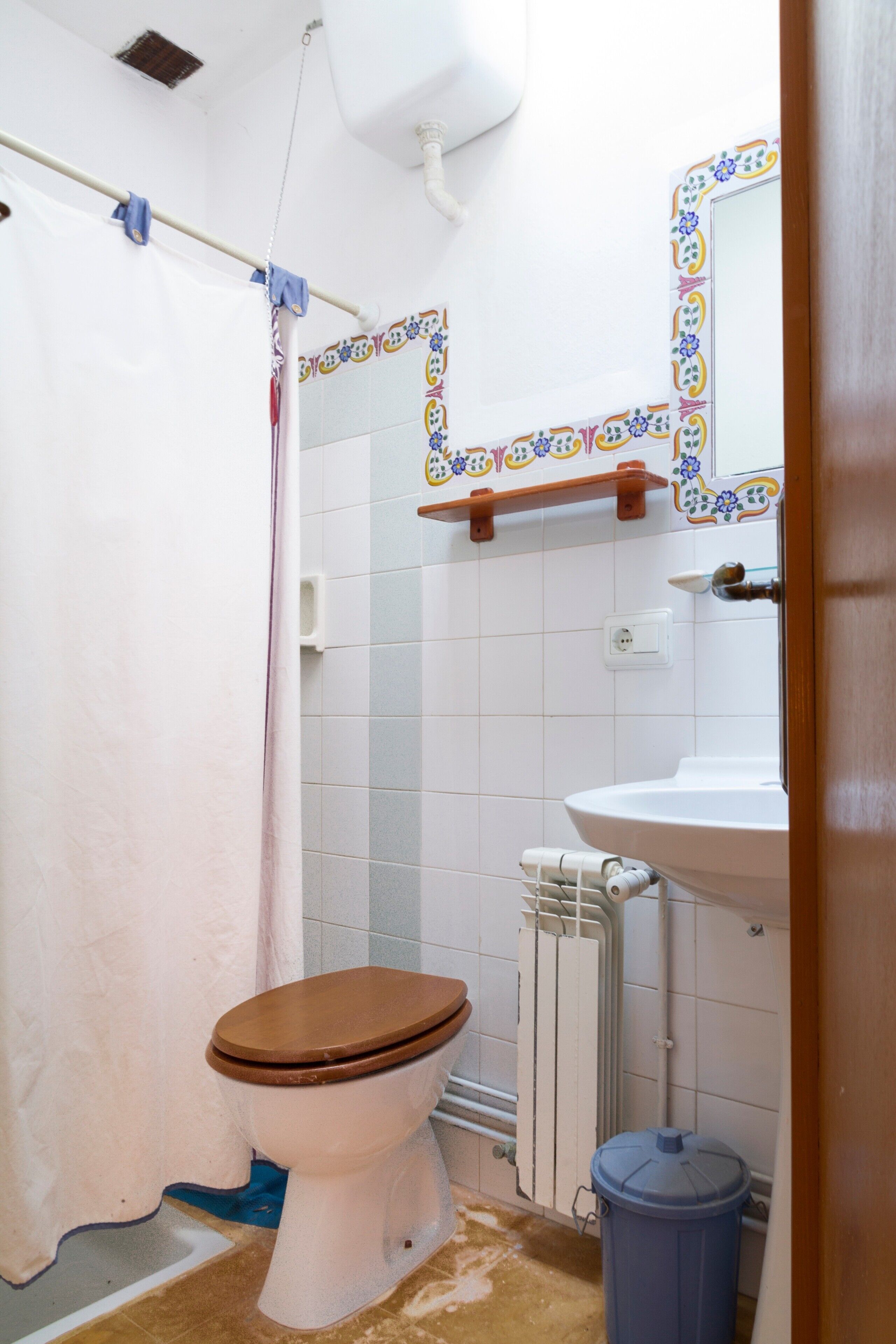 Une salle de bain équipée de toilettes, d’un lavabo, d’un rideau de douche et d’une poubelle.
