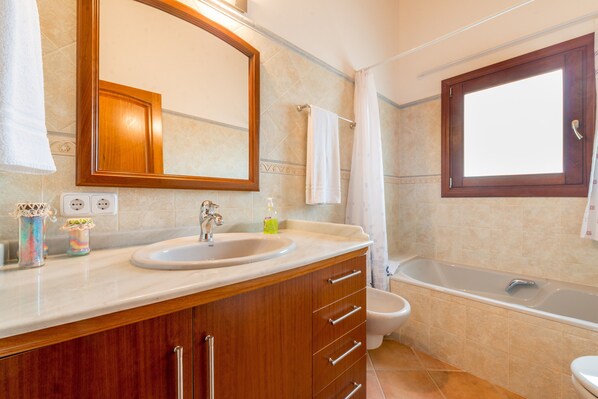 Une salle de bain équipée d’un lavabo, d’un miroir, d’un meuble-lavabo, de toilettes et d’une baignoire.