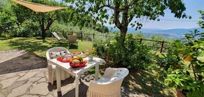 An outdoor dining area with a table set for two, surrounded by greenery and a scenic view. - Stunning private villa with internet, A/C, hot tub, TV, pets allowed, panoramic view, close to Lucca (Petrognano)