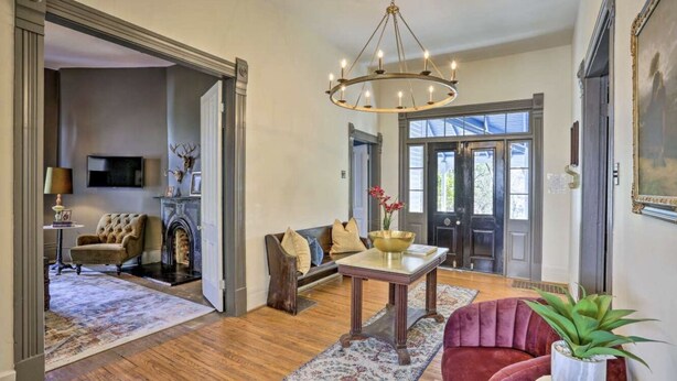 A spacious living room with a fireplace, a sofa set, a dining table, and a chandelier. - Historic charm in St. Elmo 3BR/3BA situated on over an acre at base of Lookout (Chattanooga)