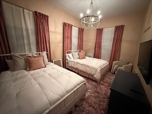 A hotel room with two beds, a chandelier, a television, and a patterned carpet. - Historic charm in St. Elmo 3BR/3BA situated on over an acre at base of Lookout (Chattanooga)