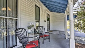 A covered porch with two wicker chairs and a small table, a window with lace curtains, and a door with a wreath. - Historic charm in St. Elmo 3BR/3BA situated on over an acre at base of Lookout (Chattanooga)