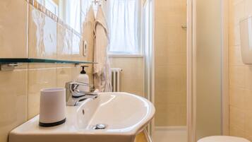 Un bagno con lavandino, specchio, porta asciugamani e zona doccia.