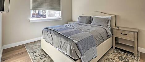A bedroom with a bed, a nightstand, a window, and a ceiling fan.