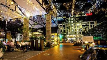 An outdoor area with seating and a pathway leading to a building with illuminated signage.