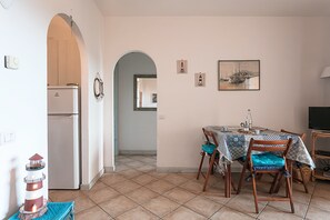 Un espace repas avec une table, des chaises et un réfrigérateur en arrière-plan.