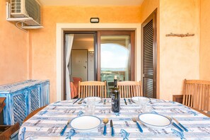 Une table à manger dressée pour quatre personnes, avec une bouteille de vin, des assiettes, des couverts et des verres.